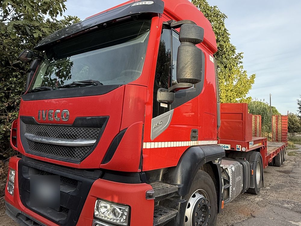 Trattore Iveco rosso con semirimorchio ribassato visto da tre quarti